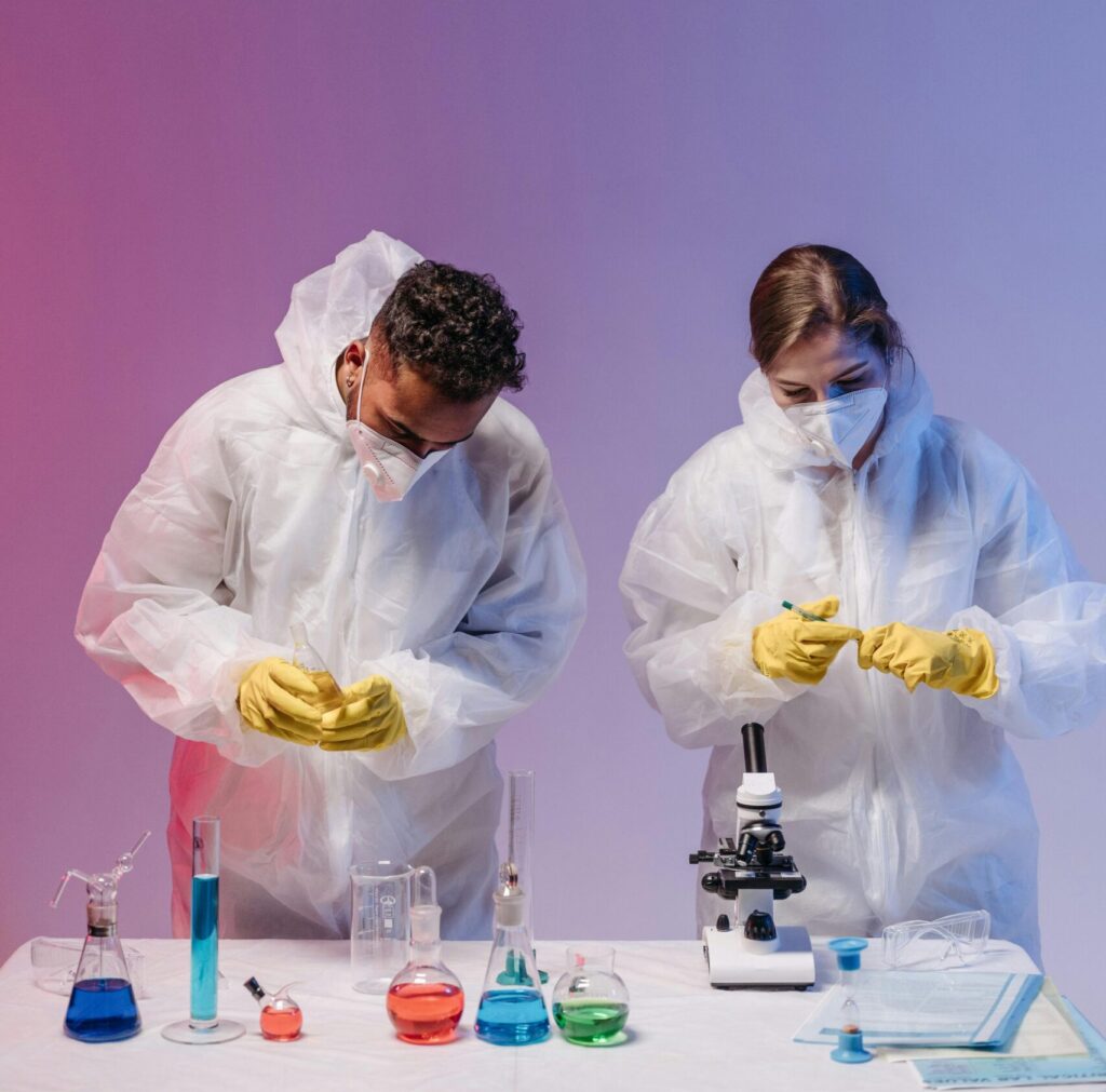 Two scientists working in a lab with protective gear and laboratory equipment.